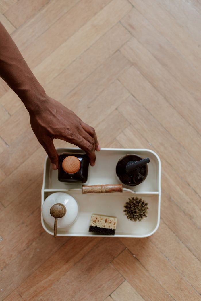 why-choose-us Hand selecting eco-friendly cleaning supplies on wooden parquet floor.